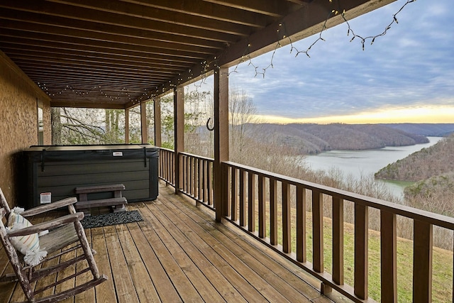 deck with a water view and a hot tub