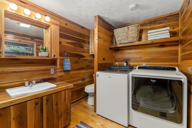 laundry room with a textured ceiling, laundry area, separate washer and dryer, and wooden walls