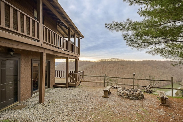 view of yard with a forest view, an outdoor fire pit, and a wooden deck