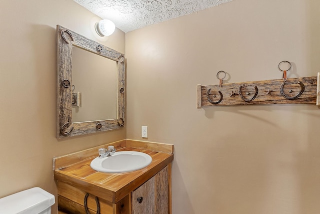 bathroom featuring toilet, a textured ceiling, and vanity