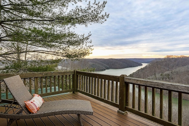 deck at dusk with a view of trees and a water and mountain view