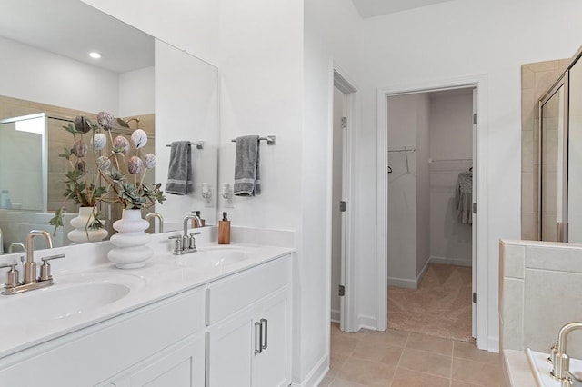 bathroom with a spacious closet, a stall shower, tile patterned flooring, and a sink