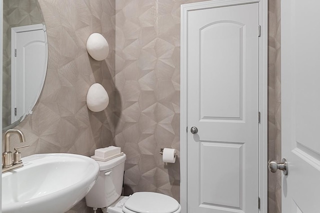 bathroom featuring toilet, tile walls, and a sink