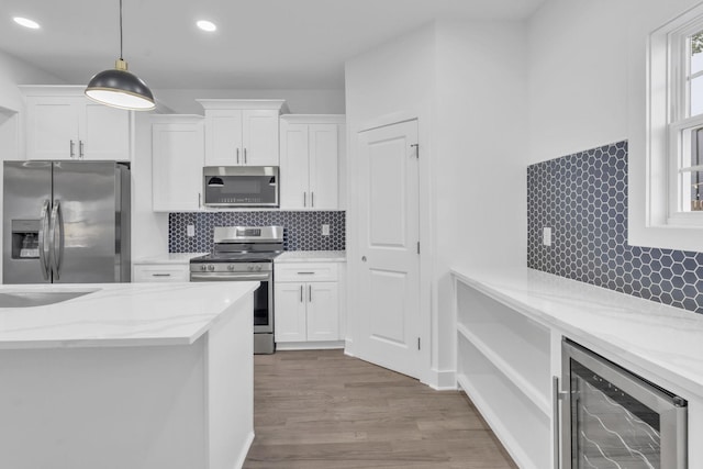 kitchen with appliances with stainless steel finishes, wine cooler, light stone counters, and white cabinets