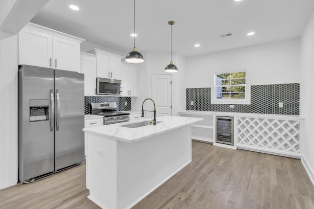 kitchen featuring a sink, visible vents, white cabinetry, appliances with stainless steel finishes, and an island with sink