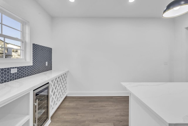 interior space featuring dark wood finished floors, a dry bar, recessed lighting, beverage cooler, and baseboards