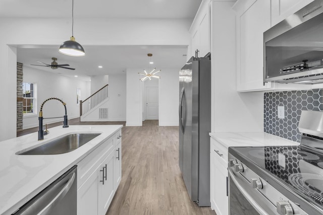 kitchen with white cabinetry, appliances with stainless steel finishes, light stone counters, and a sink