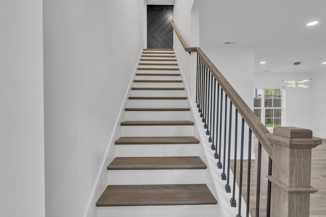 stairs with an inviting chandelier, visible vents, wood finished floors, and recessed lighting