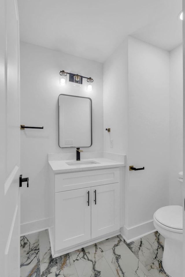 bathroom with toilet, marble finish floor, baseboards, and vanity