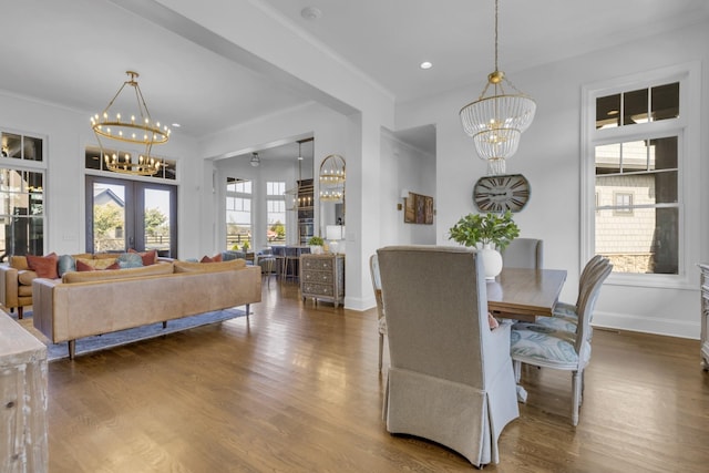 dining area with wood finished floors, baseboards, french doors, ornamental molding, and an inviting chandelier