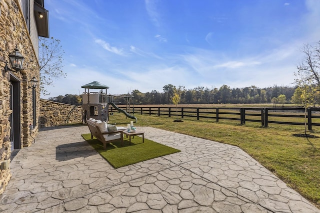 view of patio / terrace with a playground, fence, and a rural view