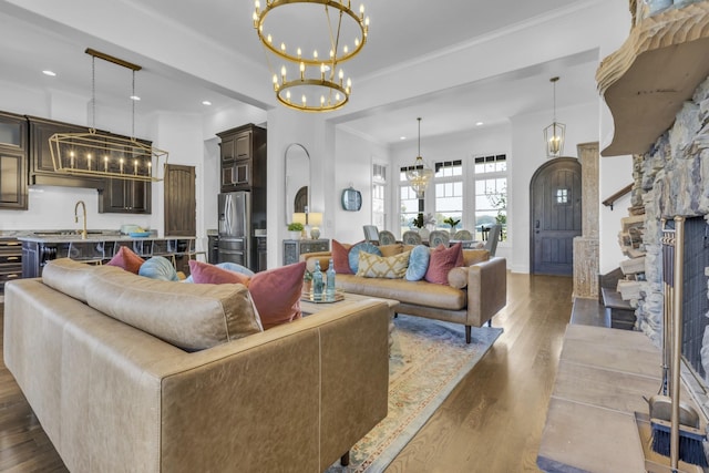 living area featuring arched walkways, dark wood-style floors, crown molding, a chandelier, and recessed lighting