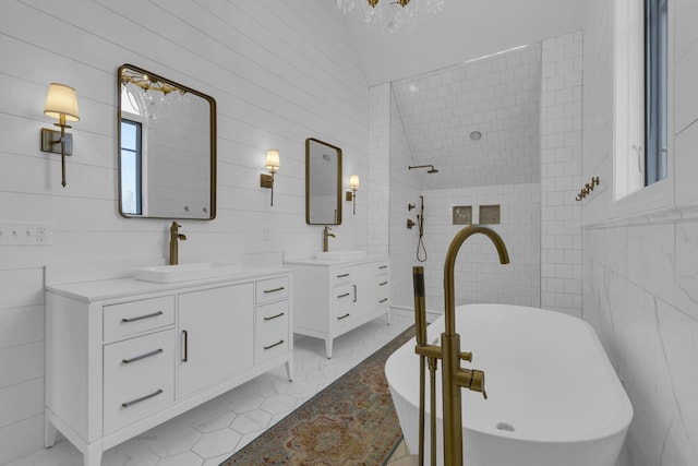 full bathroom featuring a freestanding bath, two vanities, a sink, and tile walls