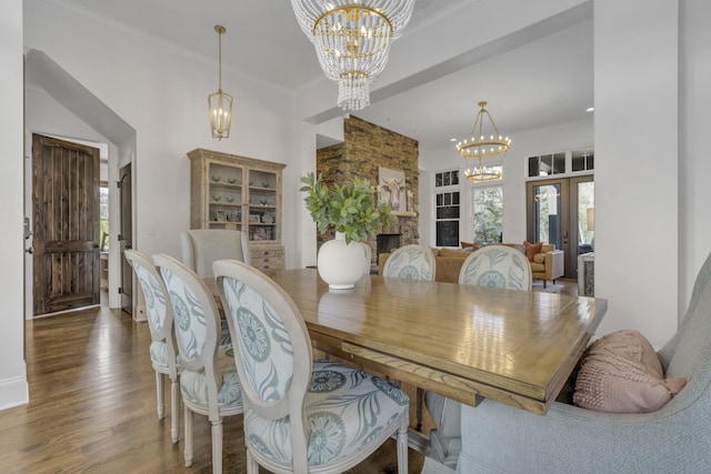 dining space featuring dark wood-style floors, a fireplace, a chandelier, and ornamental molding