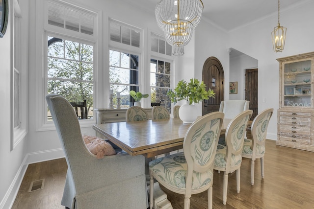 dining space featuring a chandelier, wood finished floors, visible vents, and baseboards