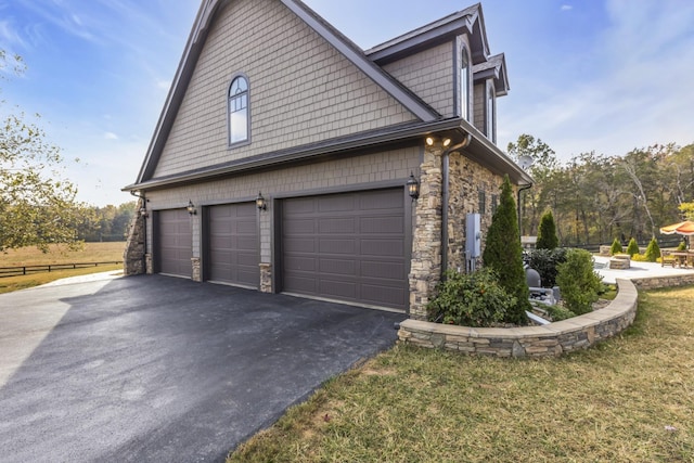 view of property exterior with a garage, stone siding, and driveway