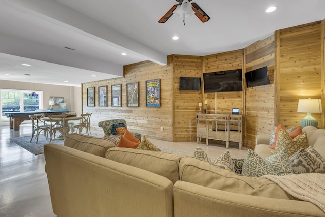 living area with ceiling fan, wood walls, concrete floors, beam ceiling, and recessed lighting