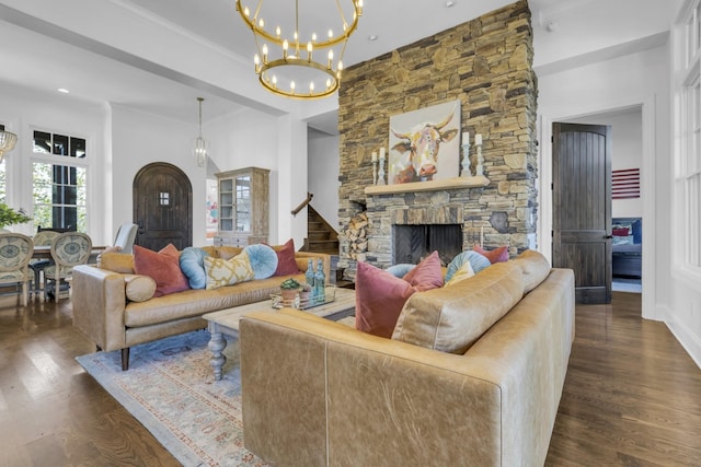 living area featuring a notable chandelier, stairs, a fireplace, and dark wood-style flooring