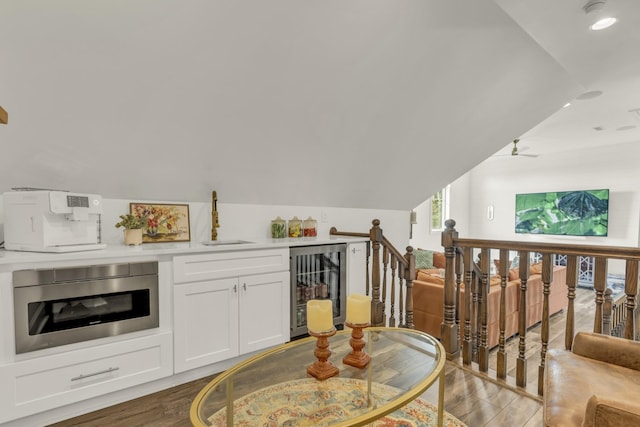 interior space featuring lofted ceiling, light wood finished floors, wine cooler, and an upstairs landing