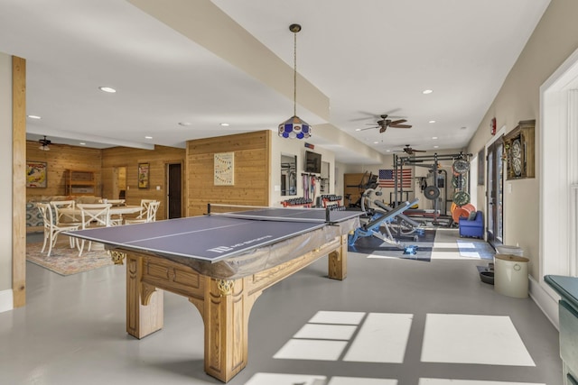 game room with finished concrete flooring, ceiling fan, recessed lighting, and wooden walls