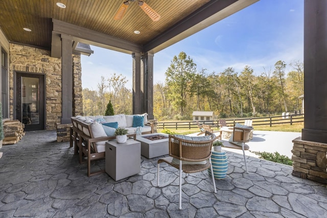 view of patio featuring a ceiling fan, an outdoor living space with a fire pit, and fence