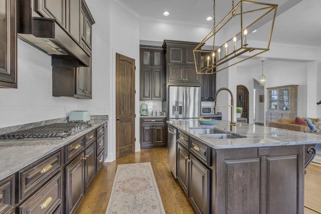 kitchen with stainless steel appliances, a sink, dark brown cabinets, an island with sink, and decorative light fixtures