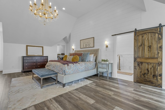 bedroom featuring a barn door, baseboards, wood finished floors, ensuite bathroom, and high vaulted ceiling