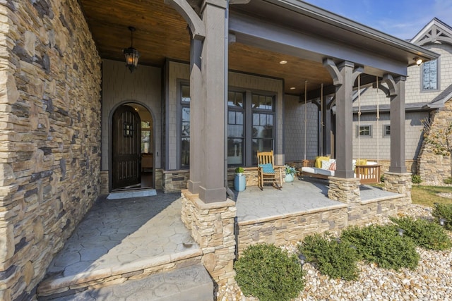 property entrance with covered porch and stone siding