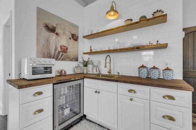 bar featuring a toaster, tasteful backsplash, a sink, wet bar, and beverage cooler