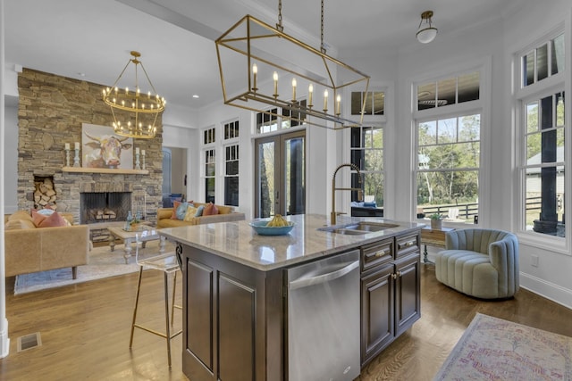 kitchen featuring dark brown cabinetry, a sink, open floor plan, dishwasher, and an island with sink