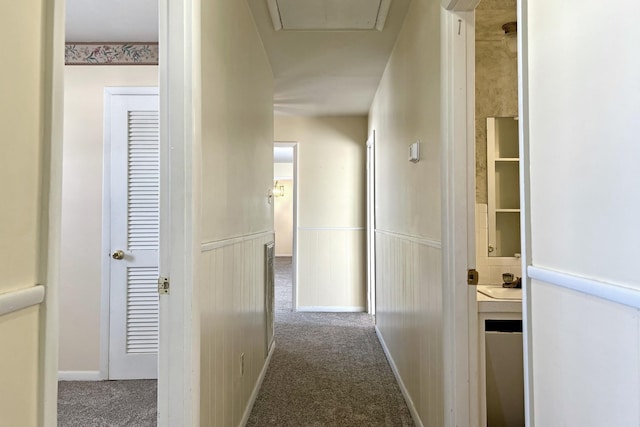 corridor with a wainscoted wall and carpet flooring