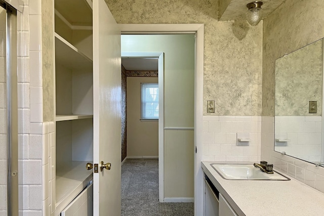 bathroom featuring baseboards, a wainscoted wall, vanity, and wallpapered walls