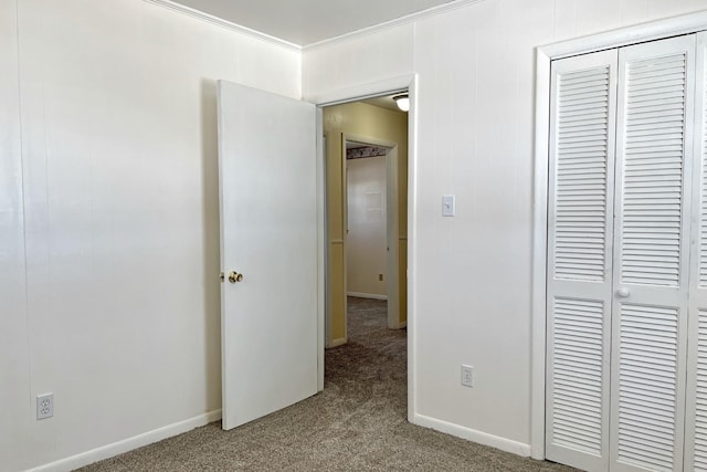 unfurnished bedroom with baseboards, a closet, carpet, and crown molding