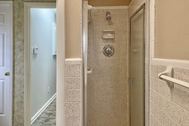 interior details with a wainscoted wall and a shower stall