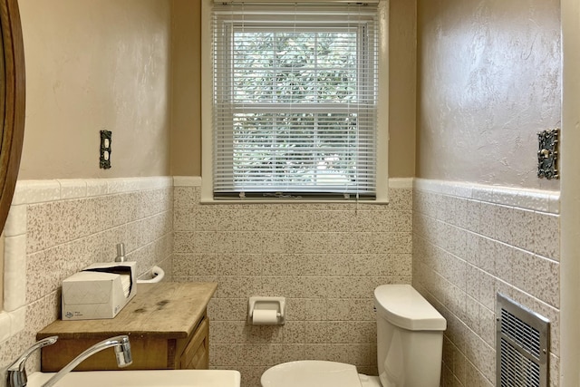 bathroom with a healthy amount of sunlight, tile walls, toilet, and a sink