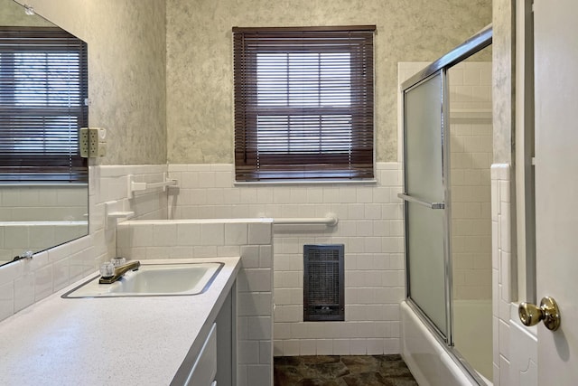 bathroom featuring enclosed tub / shower combo, tile walls, vanity, wainscoting, and heating unit