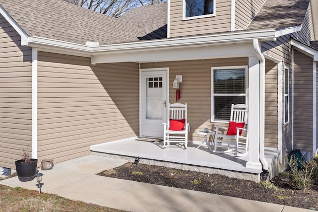 view of exterior entry featuring a shingled roof and a porch