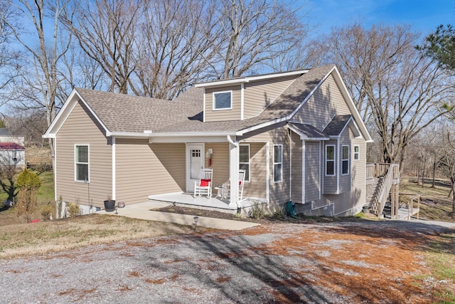 view of front of property with a shingled roof, a porch, and stairs