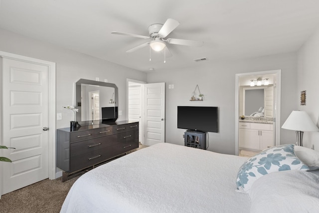 bedroom with ceiling fan, visible vents, dark carpet, and ensuite bathroom