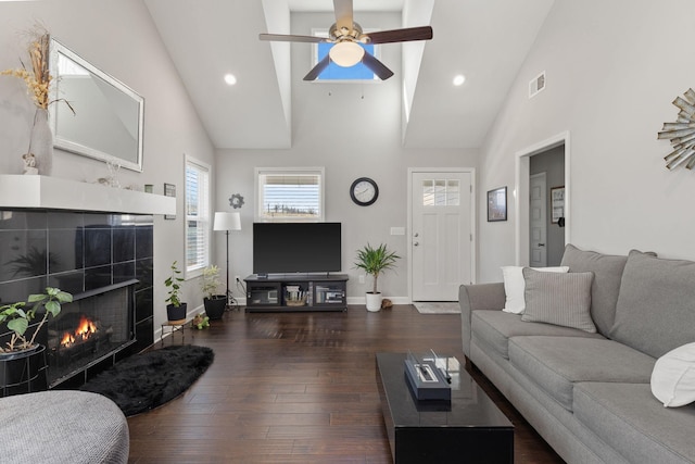 living room with a tile fireplace, visible vents, dark wood finished floors, and baseboards