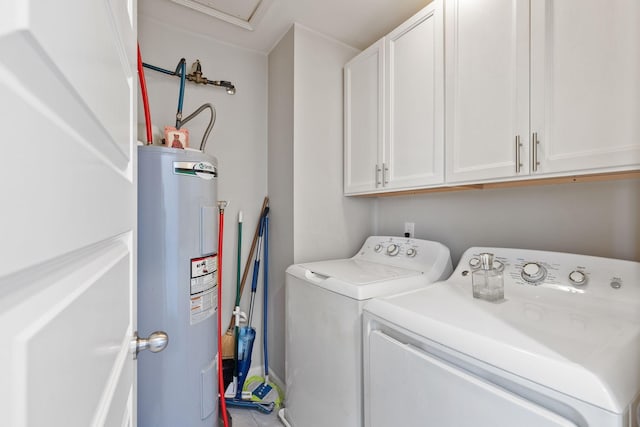 clothes washing area featuring water heater, cabinet space, and washer and clothes dryer