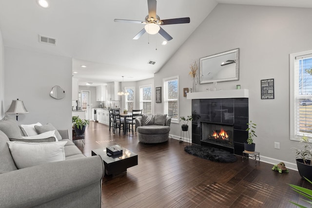 living area with high vaulted ceiling, visible vents, a wealth of natural light, and wood finished floors