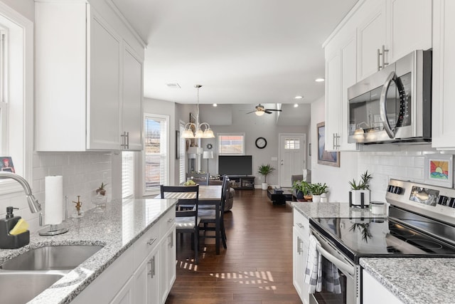 kitchen featuring dark wood-style floors, pendant lighting, appliances with stainless steel finishes, white cabinets, and a sink