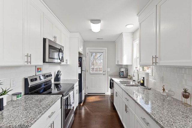 kitchen with stainless steel appliances, light stone counters, dark wood-type flooring, and white cabinets