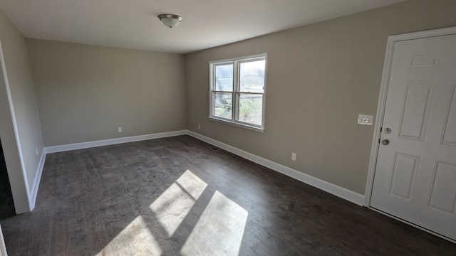 empty room featuring dark wood-style floors and baseboards