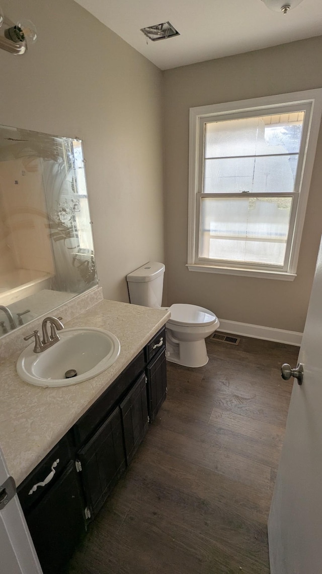 bathroom featuring baseboards, visible vents, toilet, wood finished floors, and vanity