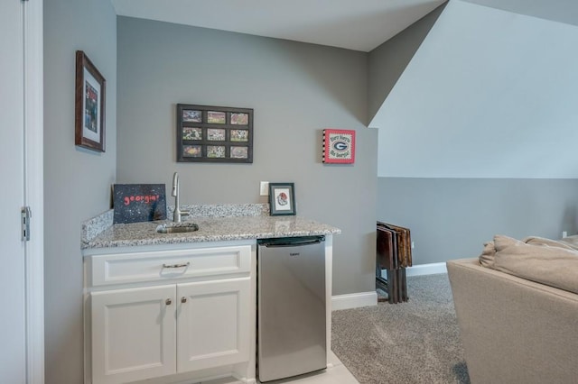 clothes washing area featuring indoor wet bar, a sink, and baseboards