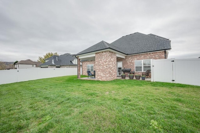 rear view of property with a patio, brick siding, a fenced backyard, and a gate