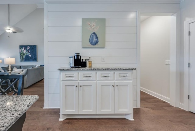 kitchen featuring dark wood-type flooring, baseboards, open floor plan, white cabinets, and light stone countertops