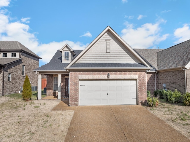 view of front of home featuring brick siding, driveway, an attached garage, and roof with shingles